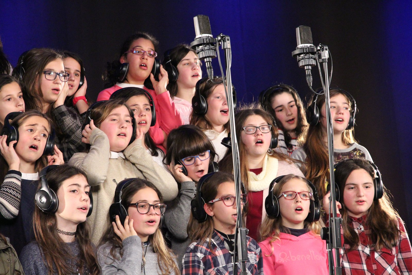 Alunos de auscultadores a cantar em frente aos microfones
