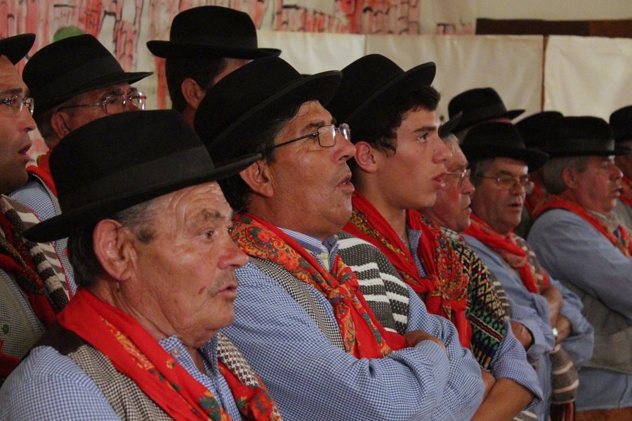Cantadores de trajes tradicionais a atuar, vistos de perfil